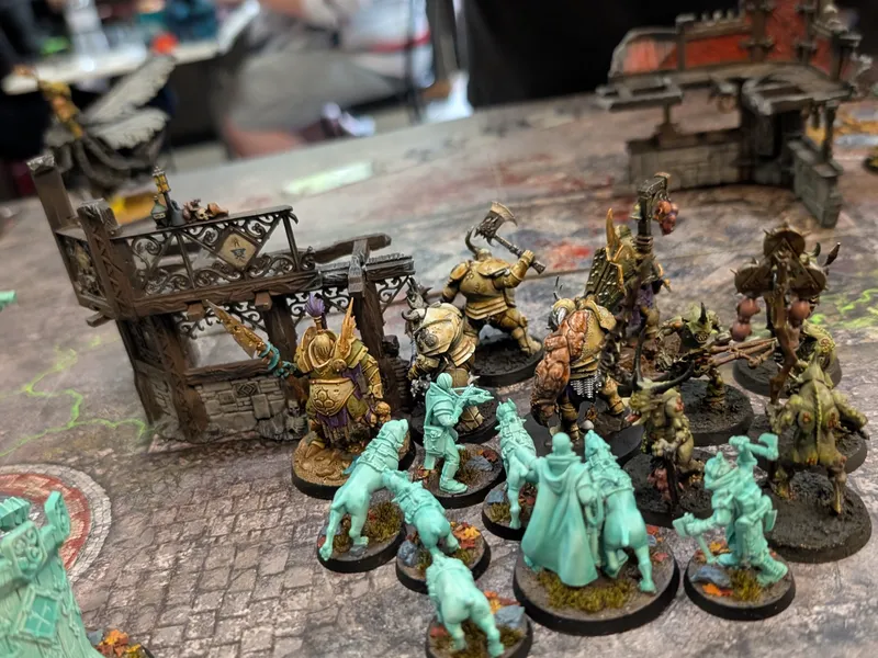 Ghostly turquoise Cities of Sigmar soldiers and hounds face Nurgle warriors beside a ruined building.