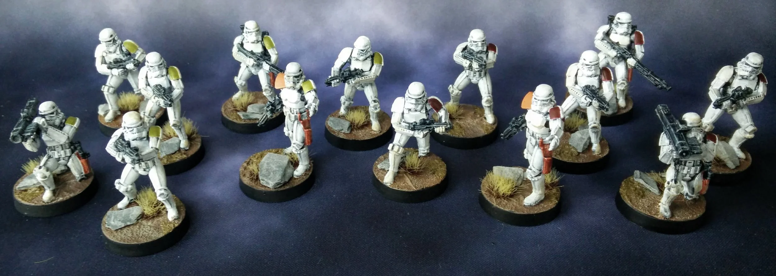 Fourteen painted Stormtrooper miniatures on desert bases, their shoulder pauldrons picked out in orange, red, and yellow.