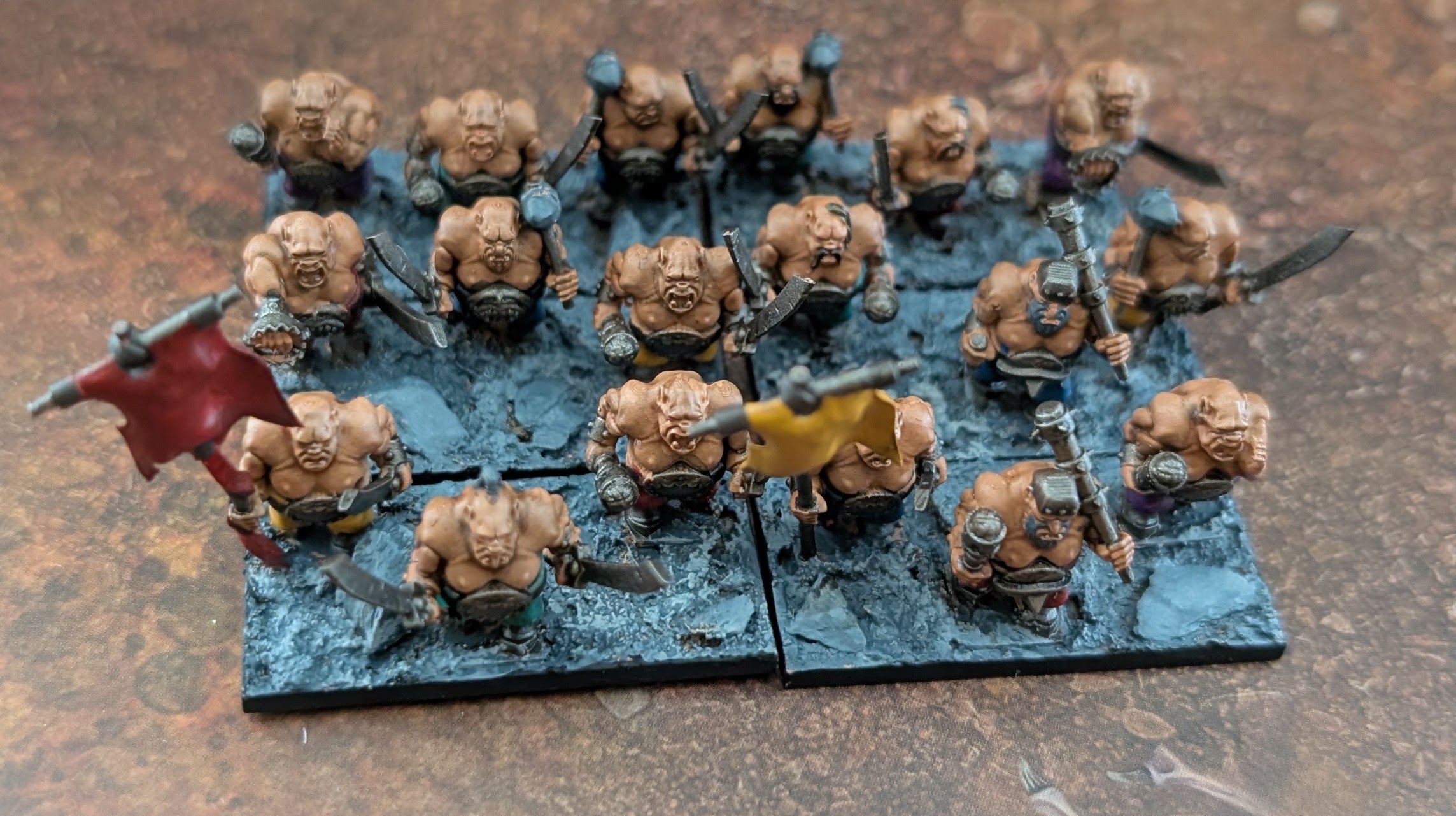 A unit of painted ogre models with banners on a large movement tray.